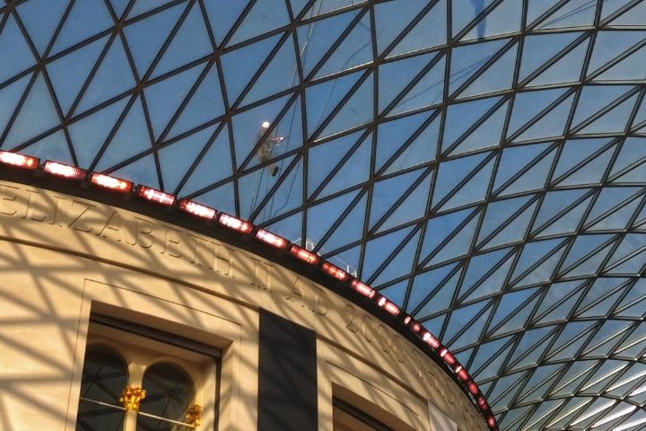 An abseiler walks across the glass roof of a Museum in London.