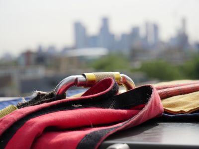 A carabiner for abseiling rests on a ledge overlooking London skyscrapers.